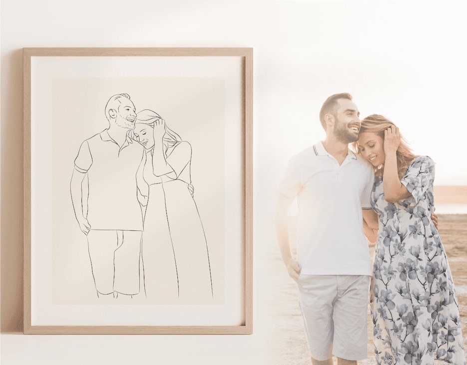 A Miroar Line Art image in an oak wood frame beside a young couple on the beach